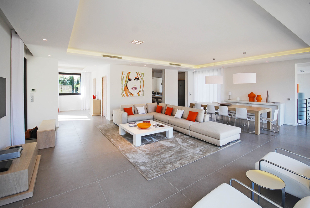 Inspiration for a contemporary open concept family room in Marseille with white walls and grey floor.