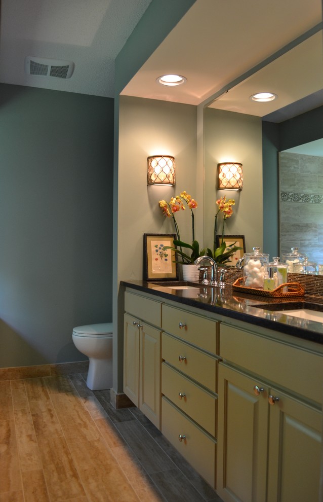 Design ideas for a mid-sized traditional master bathroom in Minneapolis with raised-panel cabinets, green cabinets, blue walls, light hardwood floors, an undermount sink, granite benchtops, a drop-in tub and a corner shower.