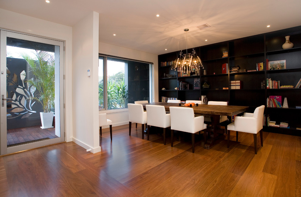 Modern dining room in Melbourne with black walls and medium hardwood floors.