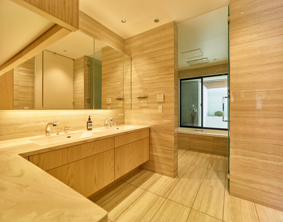 神戸にある広いアジアンスタイルのおしゃれなトイレ・洗面所 (ベージュのキャビネット、ベージュのタイル、ベージュのカウンター、造り付け洗面台) の写真