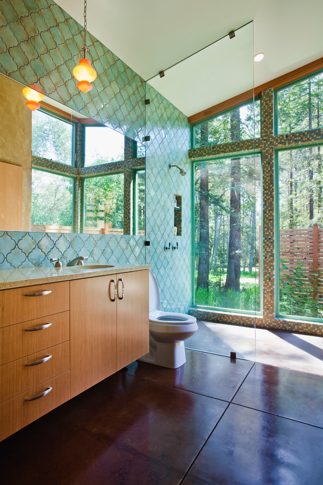 Design ideas for a mid-sized contemporary master bathroom in San Francisco with a curbless shower, an undermount sink, flat-panel cabinets, medium wood cabinets, a one-piece toilet, green tile, ceramic tile, concrete floors, recycled glass benchtops and green walls.