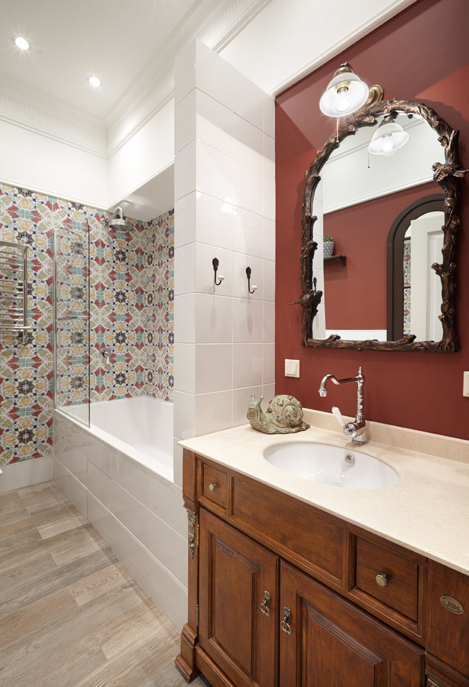 Mid-sized traditional master bathroom in Moscow with raised-panel cabinets, medium wood cabinets, marble benchtops, an alcove tub, a shower/bathtub combo, a wall-mount toilet, white tile, ceramic tile, red walls and ceramic floors.