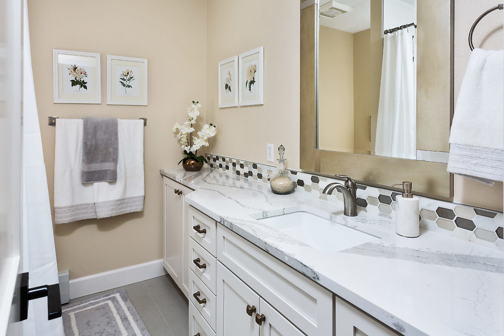 Example of a transitional bathroom design with shaker cabinets, white cabinets, beige walls, an undermount sink and quartz countertops