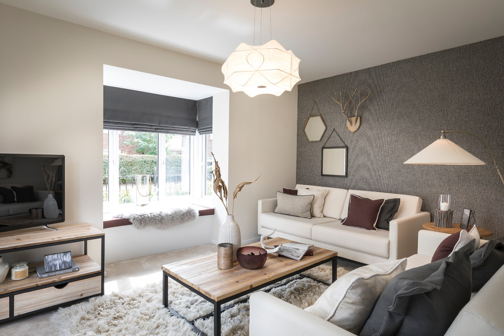 This is an example of a scandinavian living room in Manchester with beige walls, carpet, a freestanding tv and beige floor.