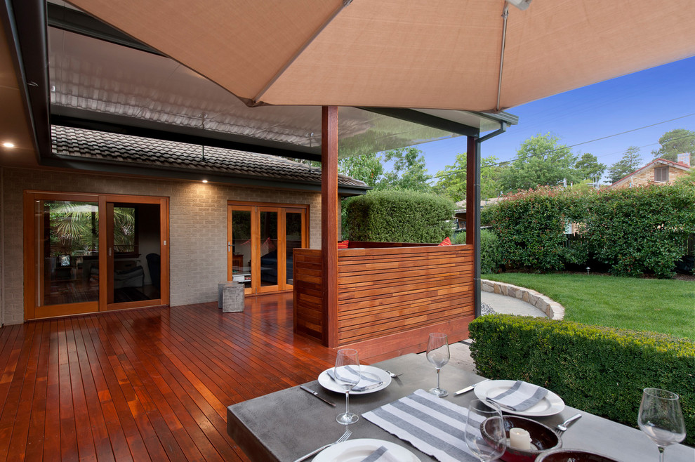 Photo of a small contemporary backyard deck in Canberra - Queanbeyan with a roof extension.