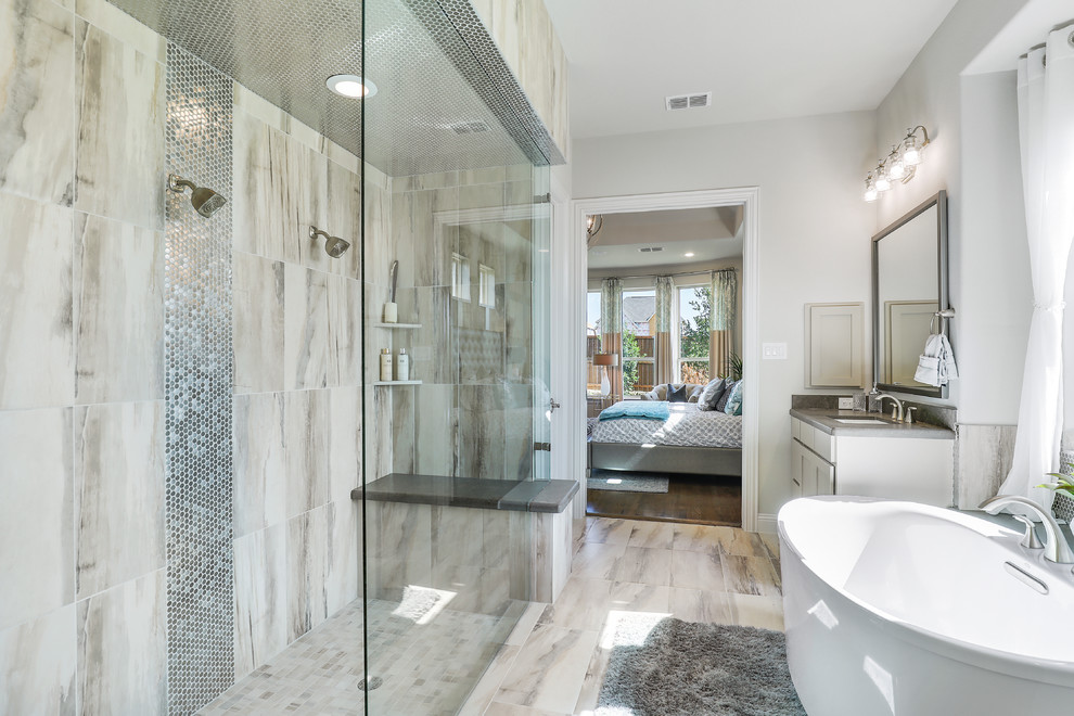 Design ideas for a mid-sized traditional master bathroom in Dallas with recessed-panel cabinets, grey cabinets, a freestanding tub, a double shower, beige tile, ceramic tile, beige walls, ceramic floors, an undermount sink, solid surface benchtops, beige floor, an open shower and grey benchtops.