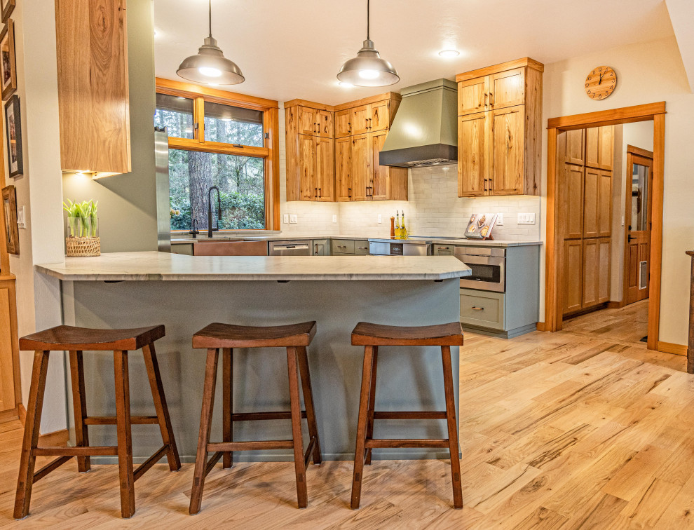 Large mountain style u-shaped light wood floor and brown floor eat-in kitchen photo with a farmhouse sink, shaker cabinets, quartzite countertops, gray backsplash, ceramic backsplash, stainless steel appliances, a peninsula and gray countertops