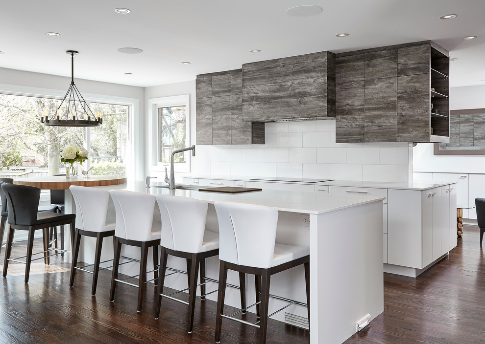 Trendy galley dark wood floor enclosed kitchen photo in Toronto with an undermount sink, flat-panel cabinets, medium tone wood cabinets, quartz countertops, white backsplash, stone tile backsplash, paneled appliances and an island