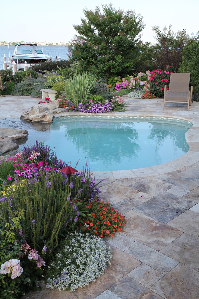 Design ideas for a traditional custom-shaped pool in New York with natural stone pavers.