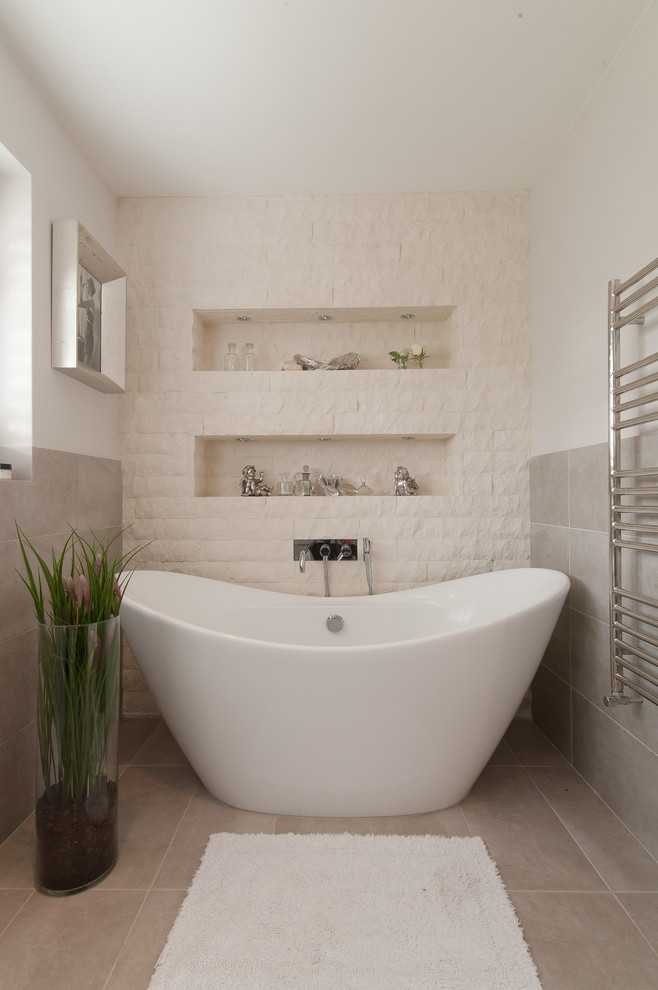 Design ideas for a transitional bathroom in Surrey with a freestanding tub, white tile, stone tile, white walls and a niche.
