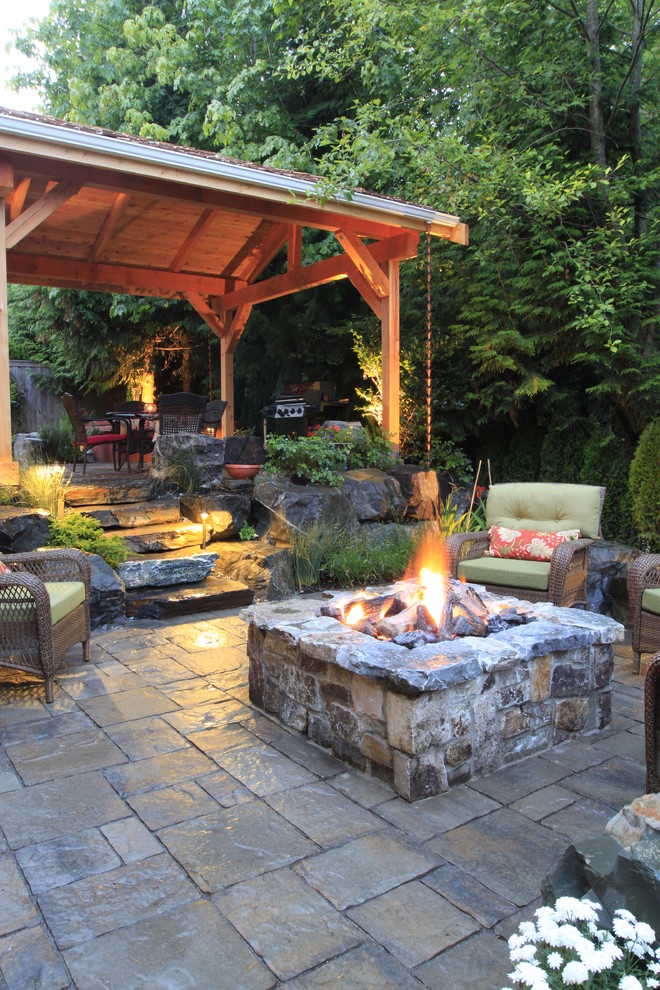 Photo of a mid-sized traditional backyard patio in Seattle with a fire feature, a gazebo/cabana and natural stone pavers.