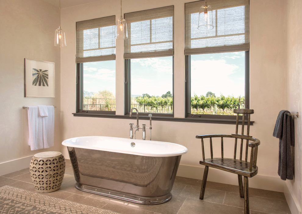 This is an example of a large contemporary master bathroom in San Francisco with a freestanding tub, white walls, limestone floors and grey floor.