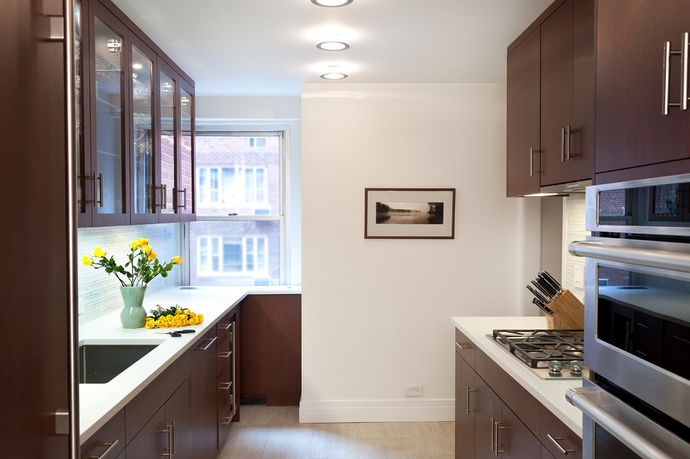 Example of a trendy galley porcelain tile enclosed kitchen design in New York with an undermount sink, glass-front cabinets, dark wood cabinets, quartz countertops, white backsplash, paneled appliances and no island