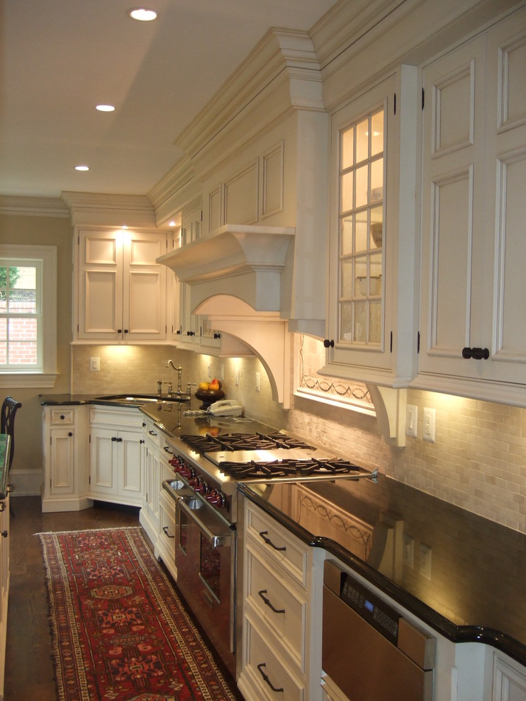 This is an example of a traditional kitchen in DC Metro with recessed-panel cabinets, stainless steel appliances and travertine splashback.