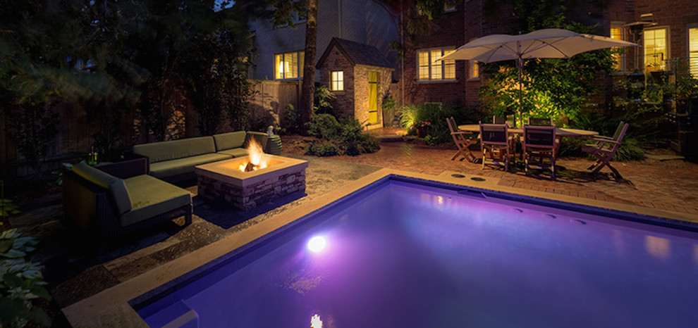 This is an example of a mid-sized transitional backyard l-shaped natural pool in Toronto with brick pavers and a hot tub.