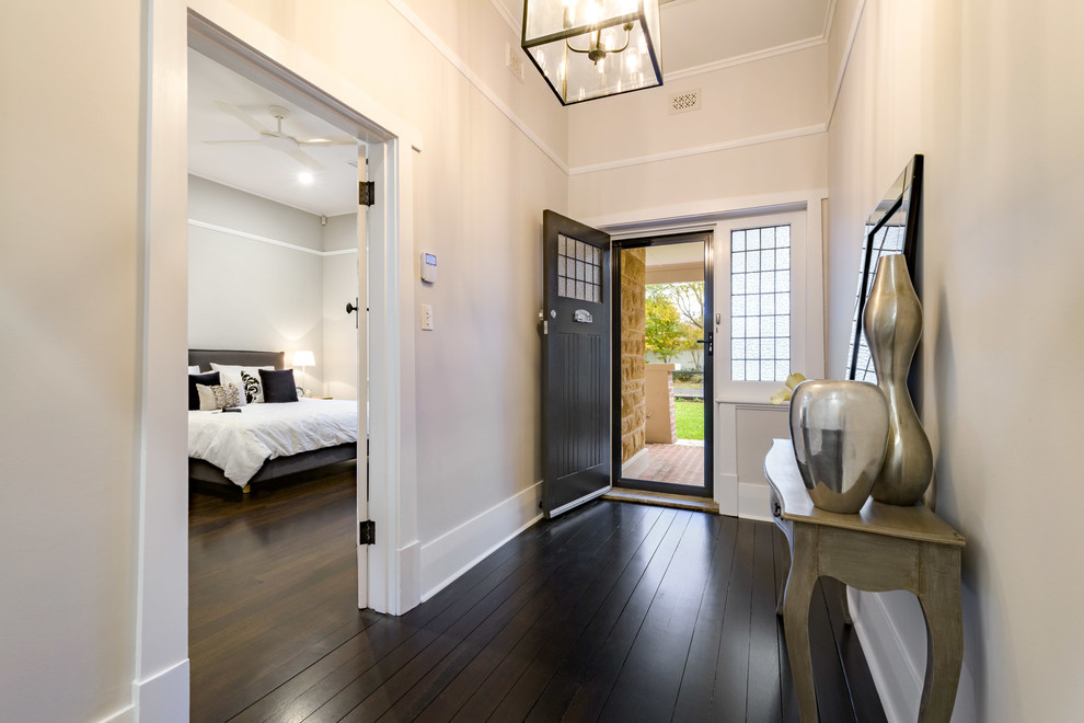 This is an example of a mid-sized modern foyer in Adelaide with black walls, dark hardwood floors, a single front door and a dark wood front door.