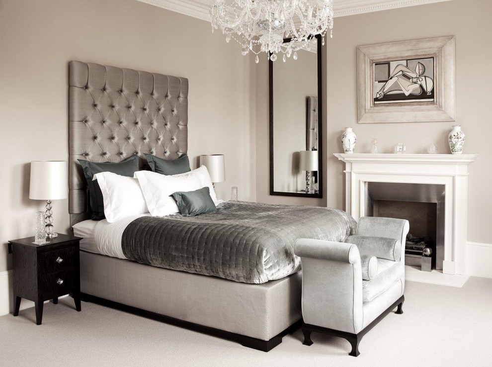 Photo of a transitional master bedroom in London with grey walls, carpet, a standard fireplace, a stone fireplace surround and grey floor.