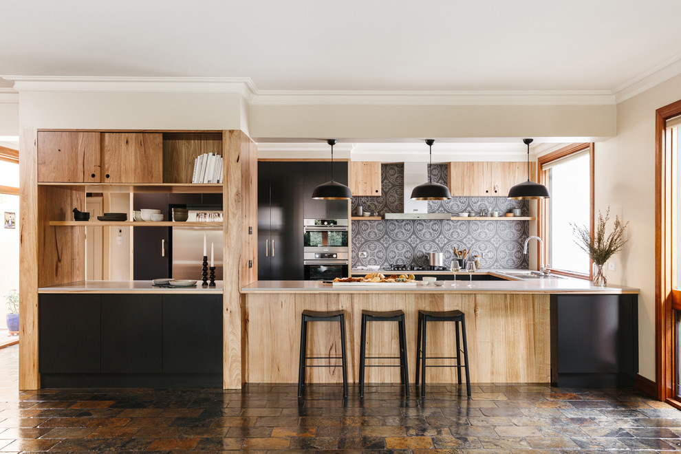 Photo of a large modern u-shaped open plan kitchen in Adelaide with flat-panel cabinets, medium wood cabinets, solid surface benchtops, grey splashback, ceramic splashback, stainless steel appliances, slate floors, with island and multi-coloured floor.
