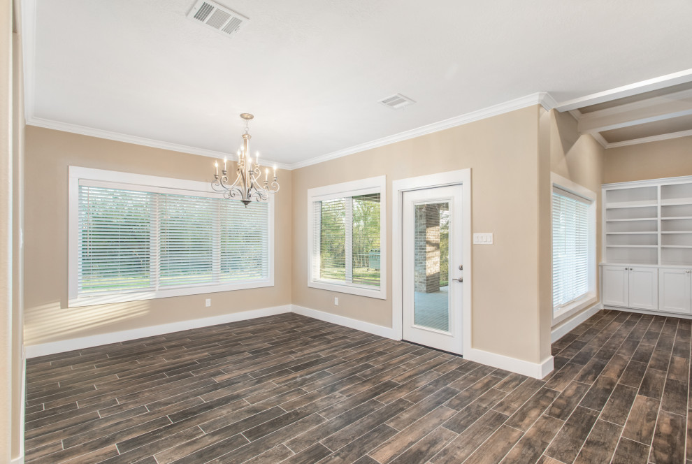 Immagine di una sala da pranzo aperta verso la cucina american style con pareti beige, parquet scuro, cornice del camino in mattoni e pavimento marrone