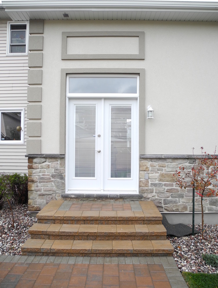 Photo of a mid-sized traditional one-storey stucco grey exterior in Ottawa.
