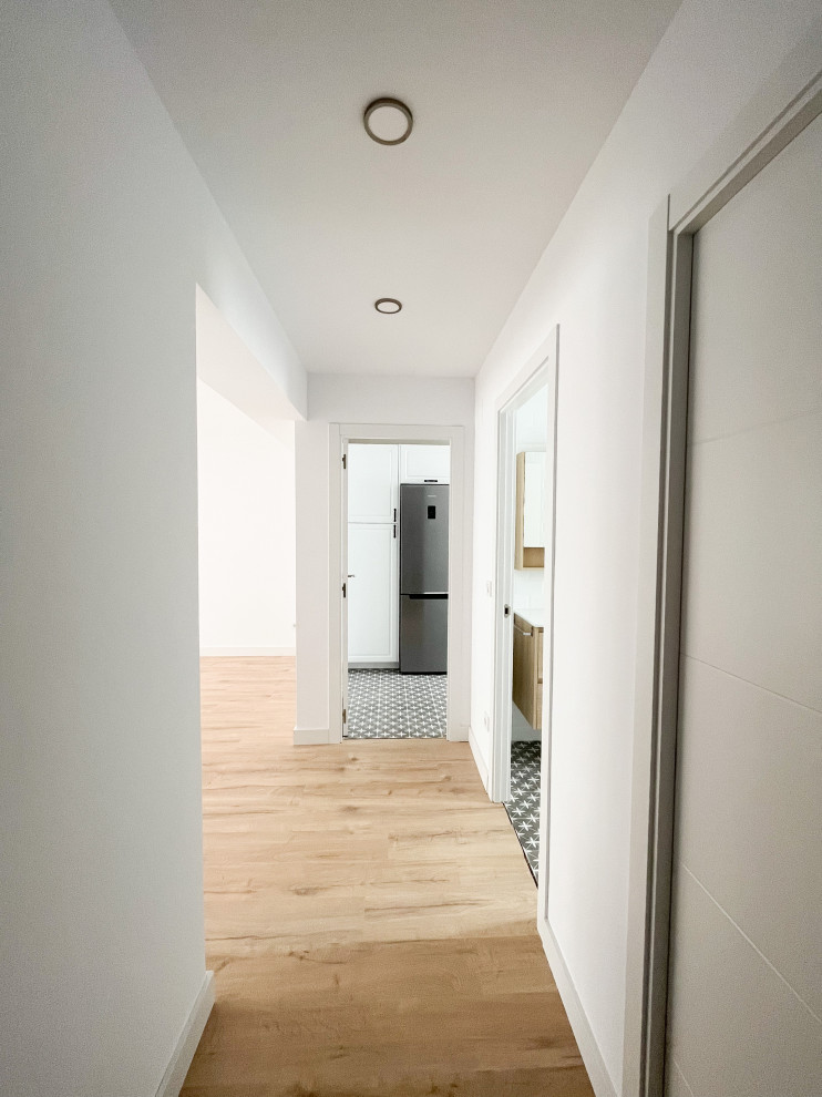 Стильный дизайн: коридор среднего размера в скандинавском стиле с белыми стенами, светлым паркетным полом и коричневым полом - последний тренд