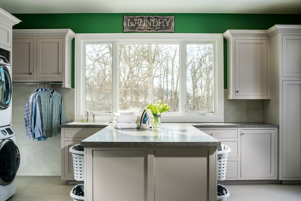 Photo of an expansive transitional u-shaped utility room in Other with green walls and a stacked washer and dryer.