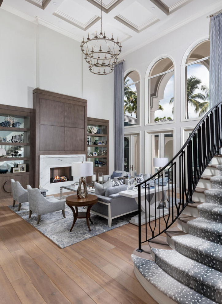 This is an example of an expansive traditional formal open plan living room in Miami with grey walls, medium hardwood flooring, a standard fireplace, a stone fireplace surround, no tv, brown floors and a coffered ceiling.