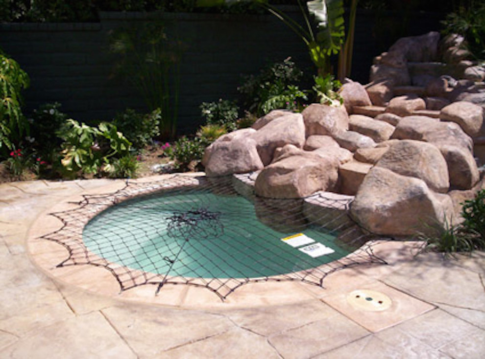 Example of a mid-sized backyard stone and round hot tub design in Miami