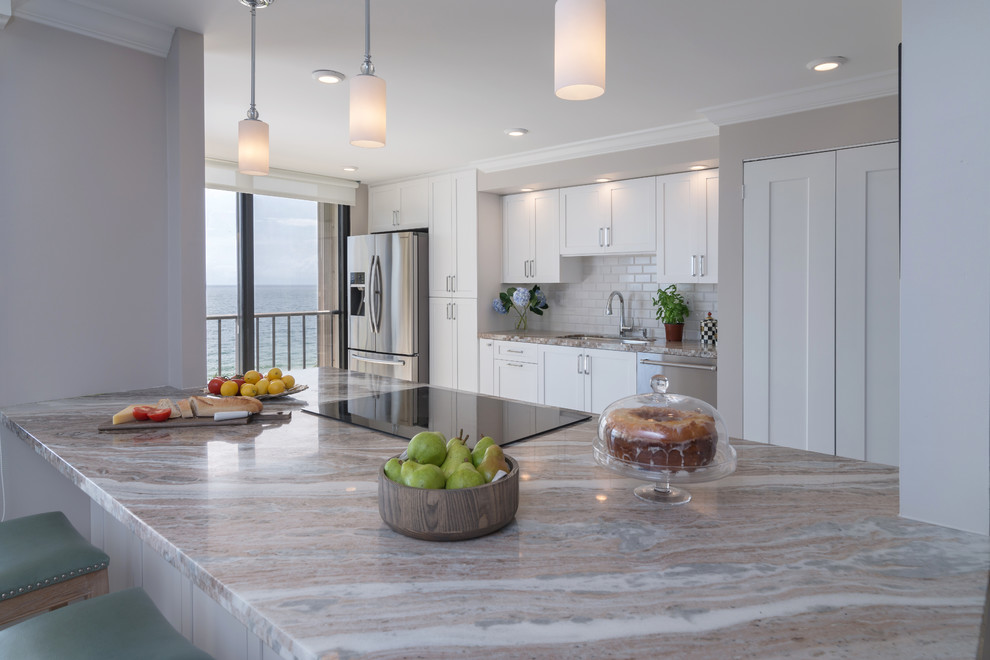 Inspiration for a mid-sized transitional galley porcelain tile eat-in kitchen remodel in Miami with an undermount sink, shaker cabinets, white cabinets, granite countertops, white backsplash, subway tile backsplash, stainless steel appliances and a peninsula