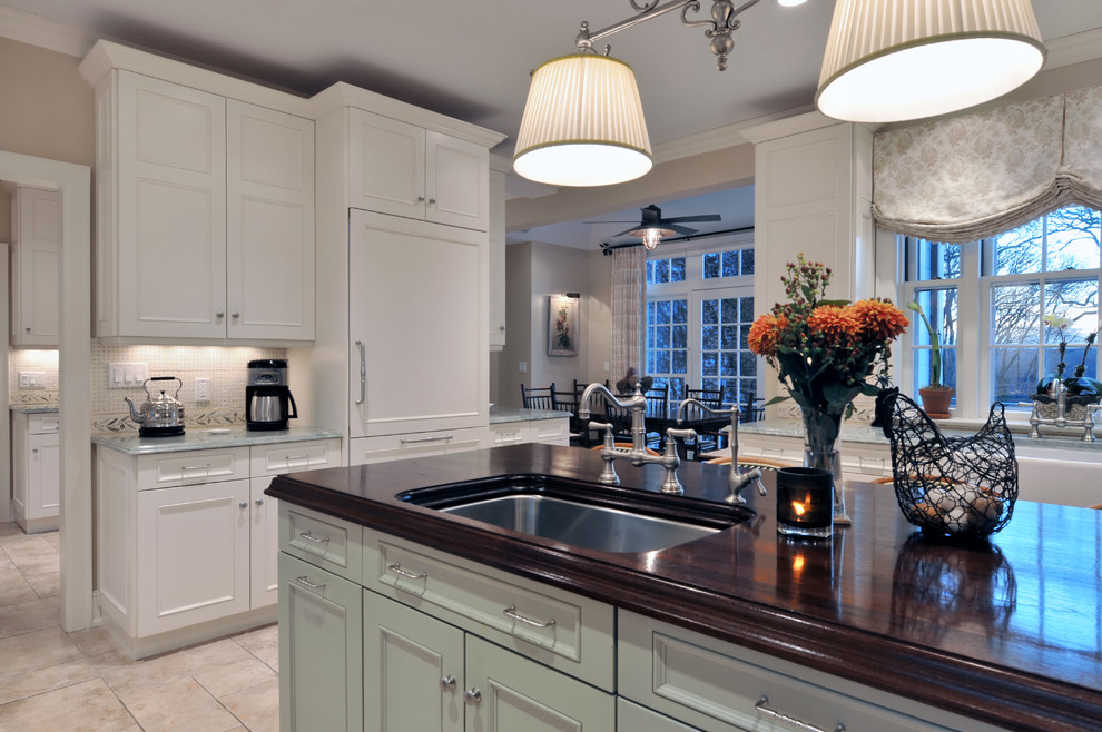 Large traditional l-shaped eat-in kitchen in New York with an undermount sink, recessed-panel cabinets, white cabinets, wood benchtops, multi-coloured splashback, ceramic splashback, stainless steel appliances, travertine floors and with island.