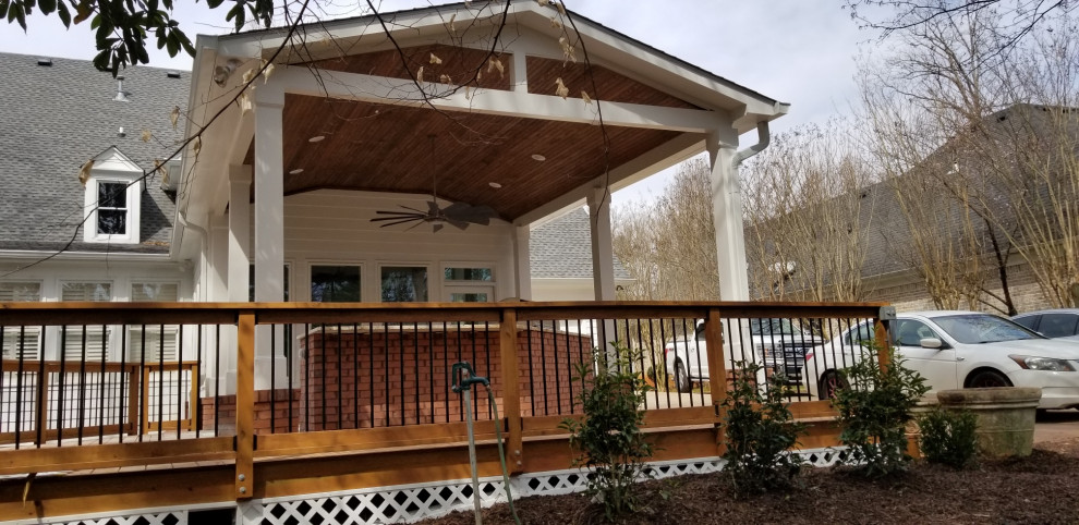 Photo of a mid-sized side yard and ground level deck in Atlanta with an outdoor kitchen, a roof extension and wood railing.