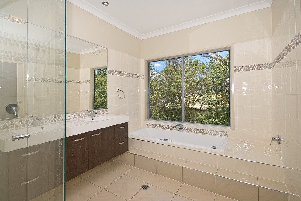 Design ideas for a large beach style master bathroom in Brisbane with flat-panel cabinets, dark wood cabinets, a drop-in tub, a corner shower, beige tile, ceramic tile, beige walls, ceramic floors, a drop-in sink and solid surface benchtops.