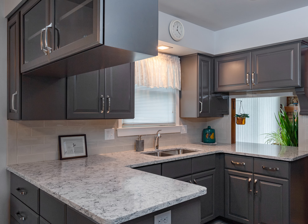 Example of a small transitional u-shaped vinyl floor and gray floor eat-in kitchen design with a double-bowl sink, raised-panel cabinets, gray cabinets, quartz countertops, white backsplash, subway tile backsplash, white appliances, no island and multicolored countertops