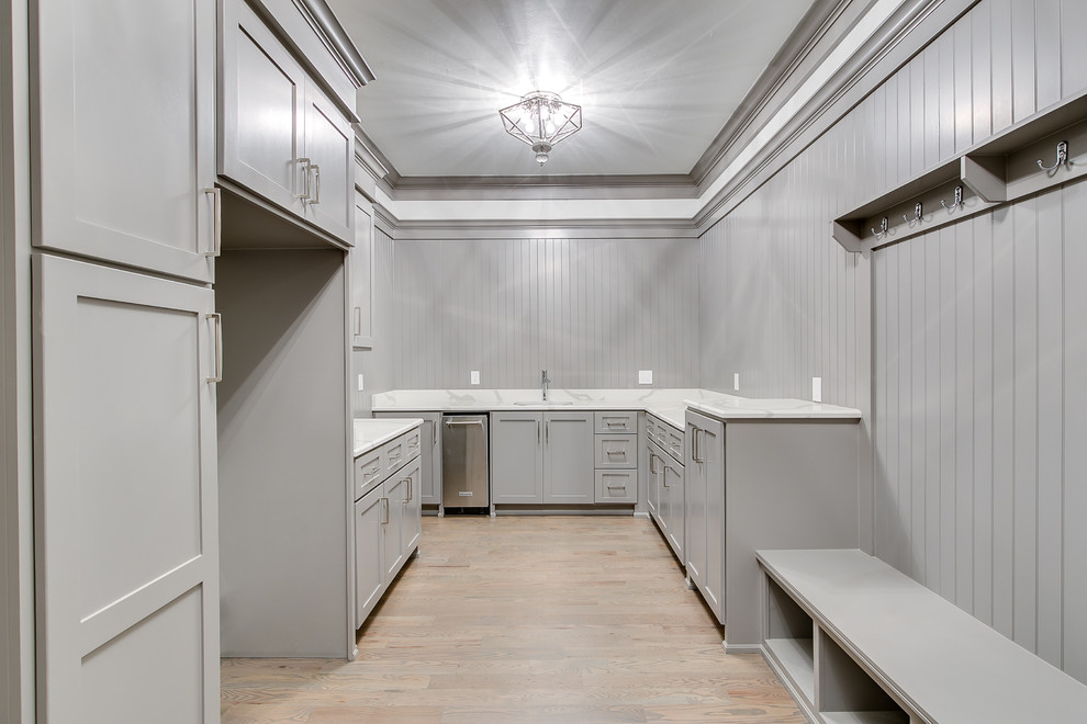 Expansive modern dedicated laundry room in Oklahoma City with shaker cabinets, grey cabinets, granite benchtops, grey walls, medium hardwood floors, a side-by-side washer and dryer and white benchtop.