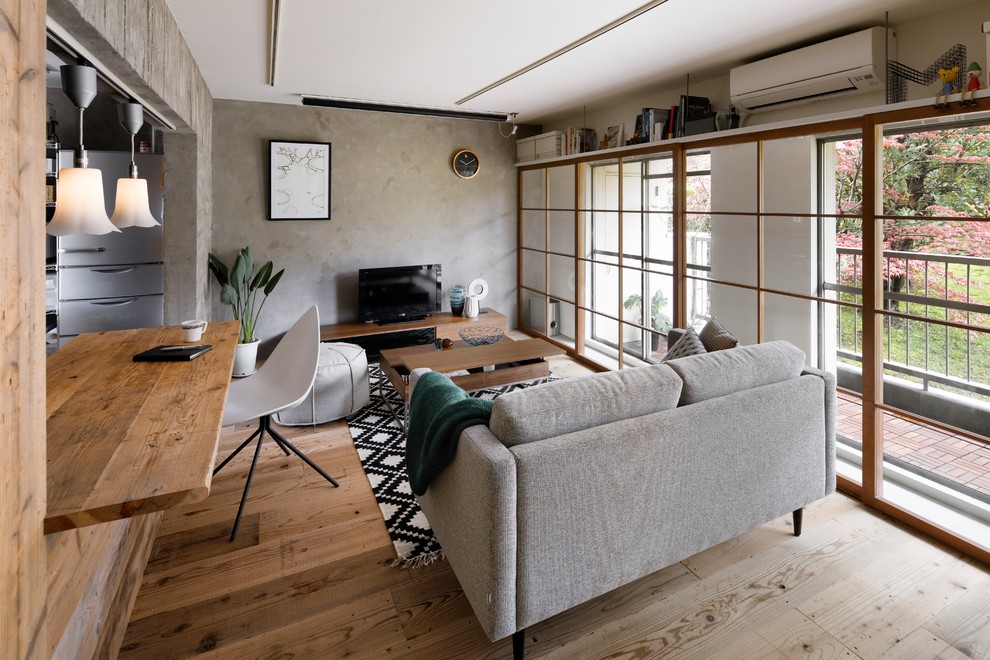 Inspiration for an industrial family room in Yokohama with grey walls, light hardwood floors, a freestanding tv and brown floor.