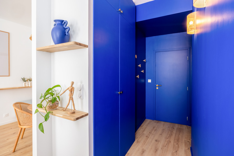 На фото: маленькая узкая прихожая в морском стиле с синими стенами, светлым паркетным полом, одностворчатой входной дверью и синей входной дверью для на участке и в саду