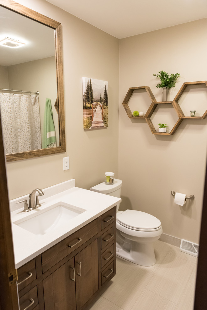 Photo of a mid-sized contemporary bathroom in Other with flat-panel cabinets, medium wood cabinets, an alcove tub, a one-piece toilet, beige tile, porcelain tile, beige walls, porcelain floors, an undermount sink and engineered quartz benchtops.
