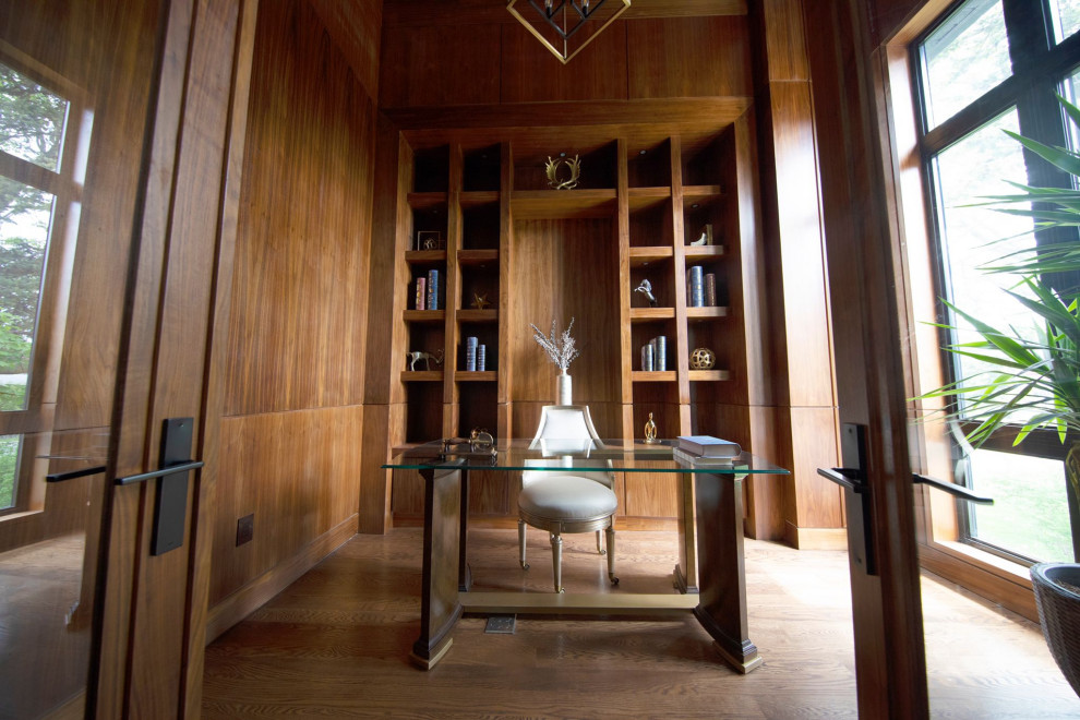 Exempel på ett stort klassiskt arbetsrum, med ett bibliotek, bruna väggar, mellanmörkt trägolv, ett fristående skrivbord och brunt golv