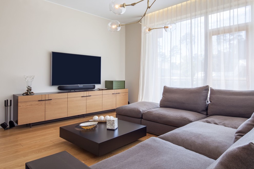 This is an example of a mid-sized modern formal living room in New York with beige walls, light hardwood floors and a wall-mounted tv.
