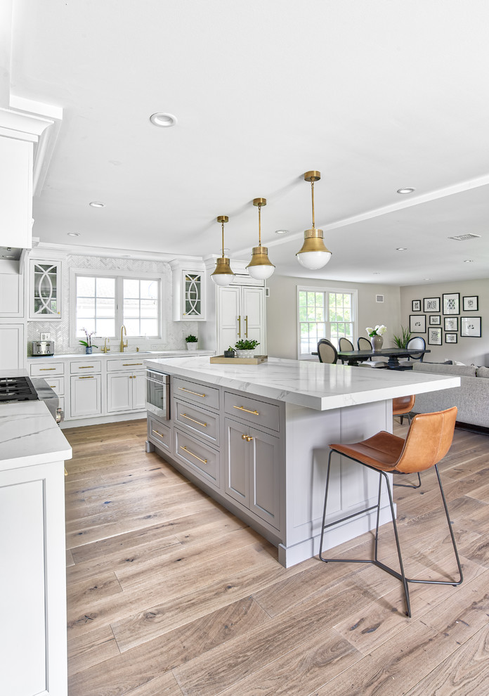 Inspiration for a large transitional l-shaped open plan kitchen in New York with an undermount sink, beaded inset cabinets, white cabinets, quartz benchtops, white splashback, mosaic tile splashback, panelled appliances, with island and white benchtop.