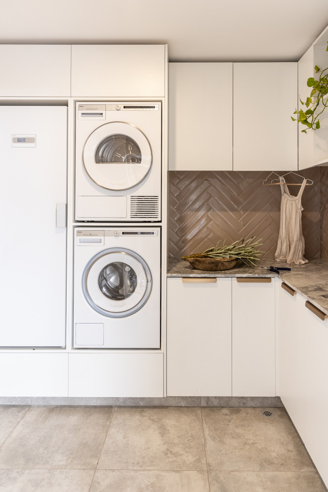 This is an example of a mid-sized contemporary dedicated laundry room in Perth with a double-bowl sink, white cabinets, marble benchtops, pink splashback, subway tile splashback, white walls, porcelain floors, a stacked washer and dryer and multi-coloured benchtop.