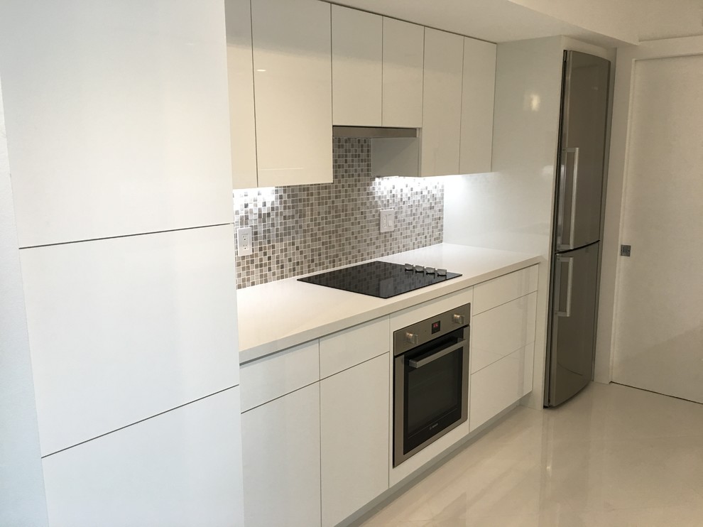 Design ideas for a modern galley kitchen in Miami with an undermount sink, flat-panel cabinets, white cabinets, quartzite benchtops, metallic splashback, mosaic tile splashback, stainless steel appliances, porcelain floors and white floor.