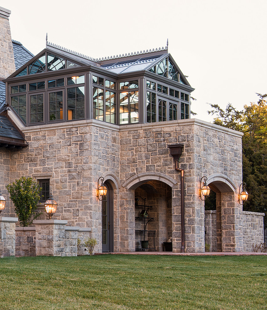 This is an example of an expansive traditional two-storey grey exterior in Denver with stone veneer and a hip roof.