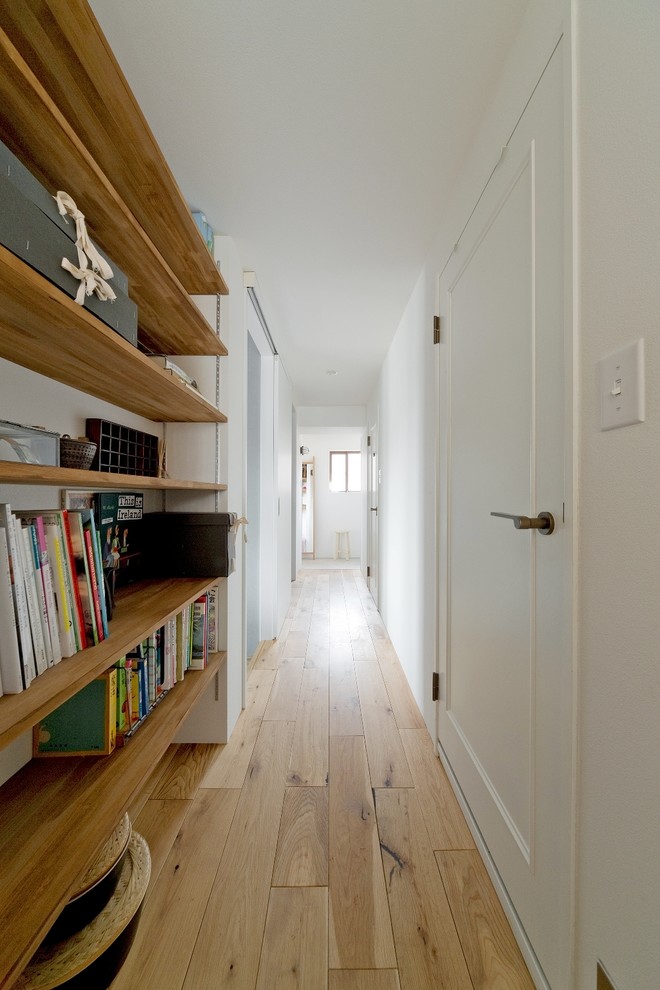 Design ideas for a scandinavian hallway in Osaka with white walls, beige floor and light hardwood floors.