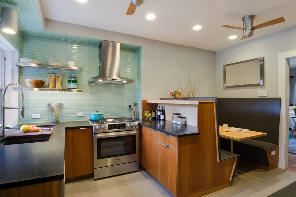 This is an example of a small modern u-shaped eat-in kitchen in Boston with an integrated sink, flat-panel cabinets, medium wood cabinets, granite benchtops, green splashback, glass tile splashback, stainless steel appliances, porcelain floors and a peninsula.