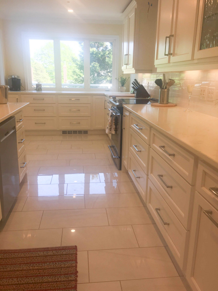 Example of a mid-sized transitional u-shaped porcelain tile and gray floor eat-in kitchen design with an undermount sink, shaker cabinets, white cabinets, quartz countertops, white backsplash, subway tile backsplash, stainless steel appliances, a peninsula and beige countertops