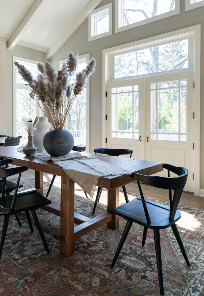 Inspiration pour une salle à manger traditionnelle avec un mur gris, parquet clair, une cheminée standard, un manteau de cheminée en plâtre, un sol marron et un plafond voûté.