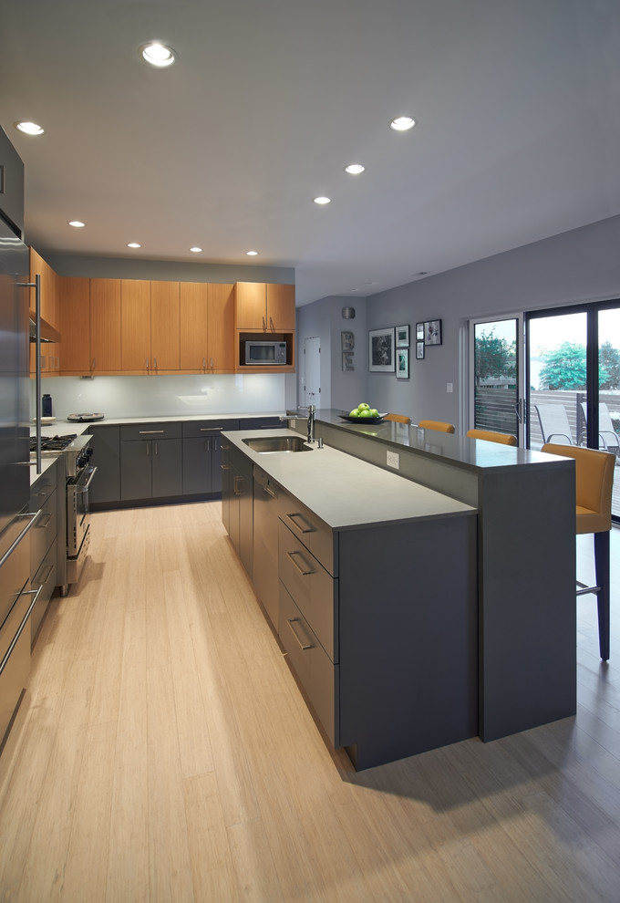 Inspiration for a mid-sized contemporary l-shaped open plan kitchen in Seattle with with island, flat-panel cabinets, light wood cabinets, quartz benchtops, blue splashback, glass sheet splashback, stainless steel appliances, an undermount sink and bamboo floors.