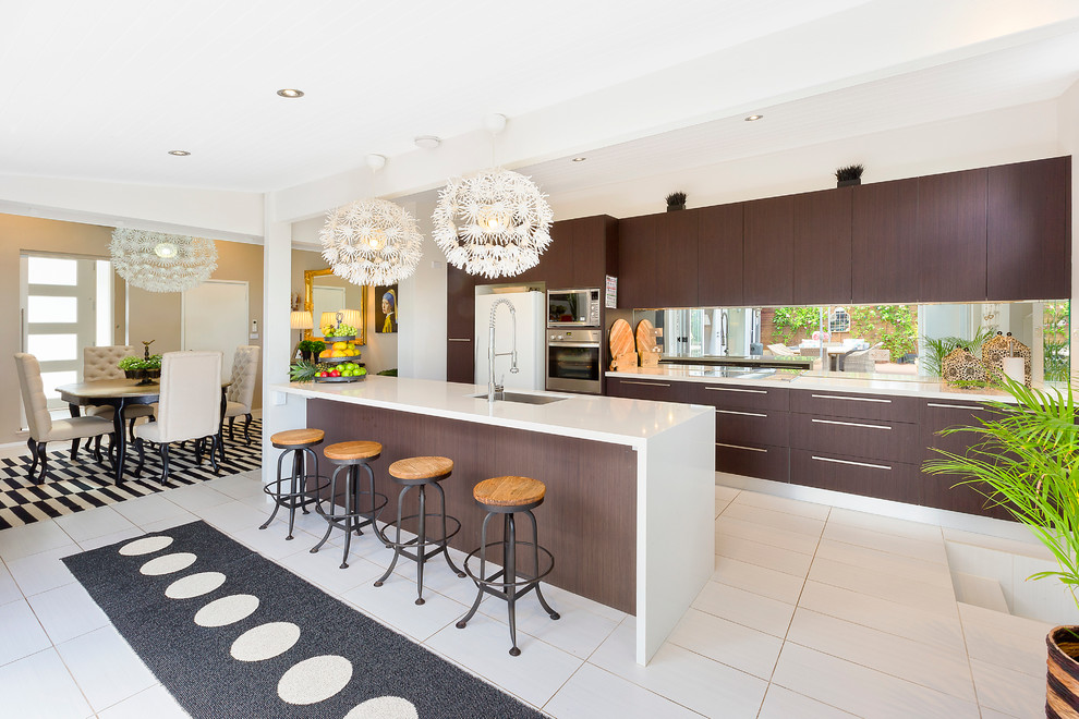 Large contemporary galley eat-in kitchen in Sydney with flat-panel cabinets, dark wood cabinets, brown splashback, mirror splashback, stainless steel appliances and with island.