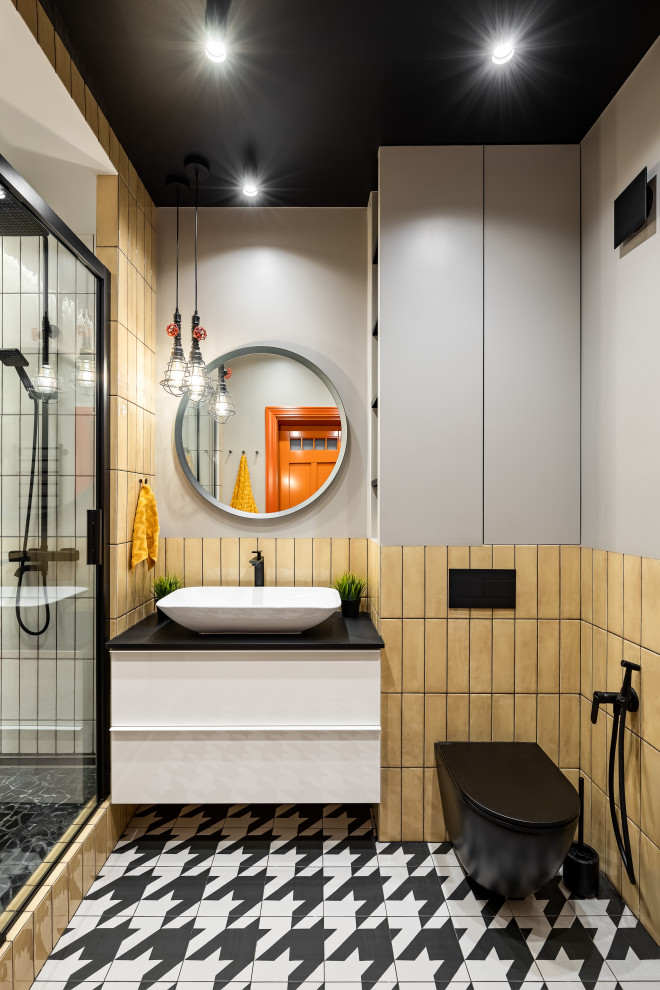Пример оригинального дизайна: маленькая главная ванная комната в современном стиле с плоскими фасадами, белыми фасадами, полновстраиваемой ванной, душем над ванной, инсталляцией, желтой плиткой, керамической плиткой, серыми стенами, полом из керамической плитки, настольной раковиной, столешницей из искусственного камня, черным полом, черной столешницей, нишей, тумбой под одну раковину и подвесной тумбой для на участке и в саду